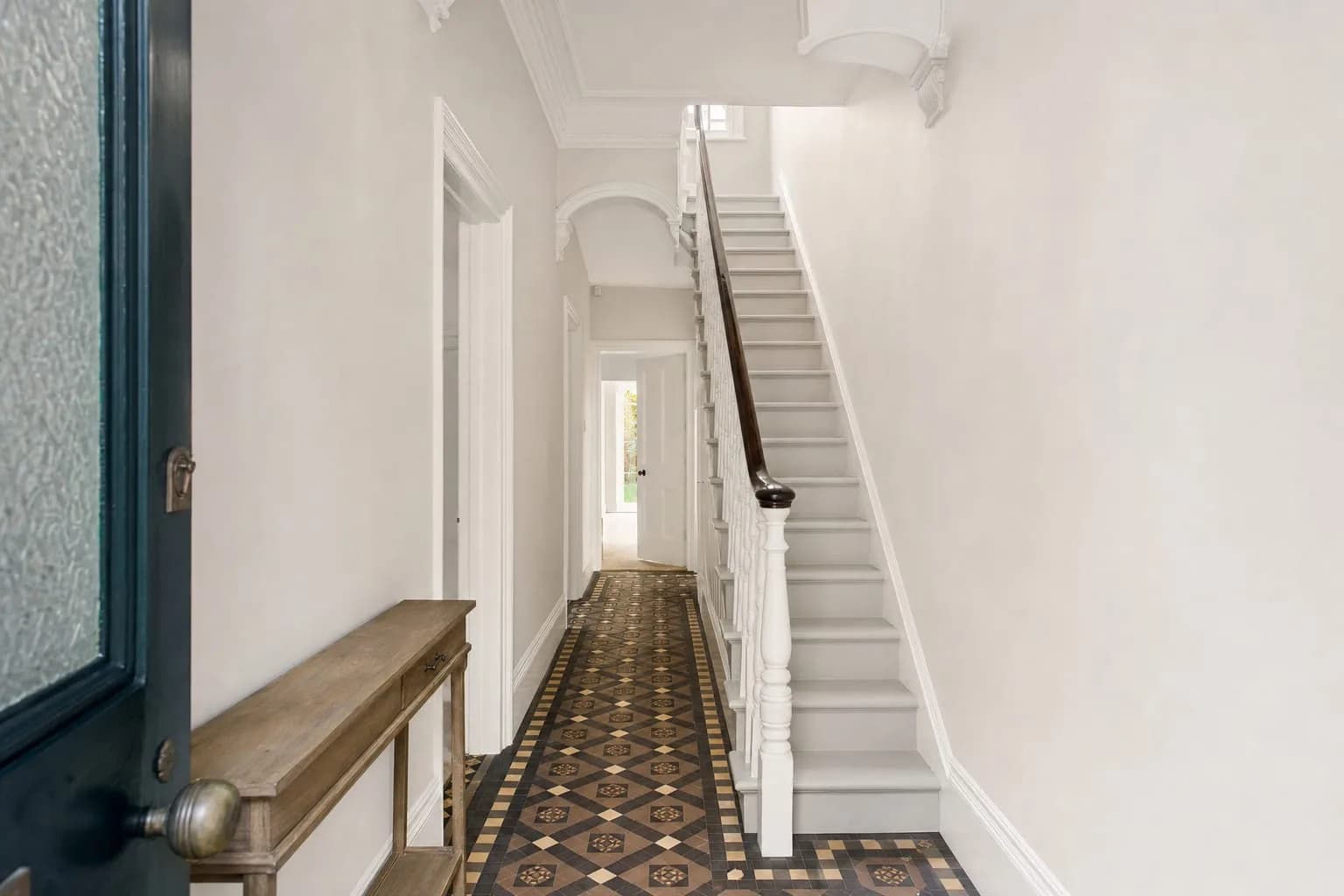 After: the hallway with smooth off-white walls, crisp white woodwork and a clean tiled floor
