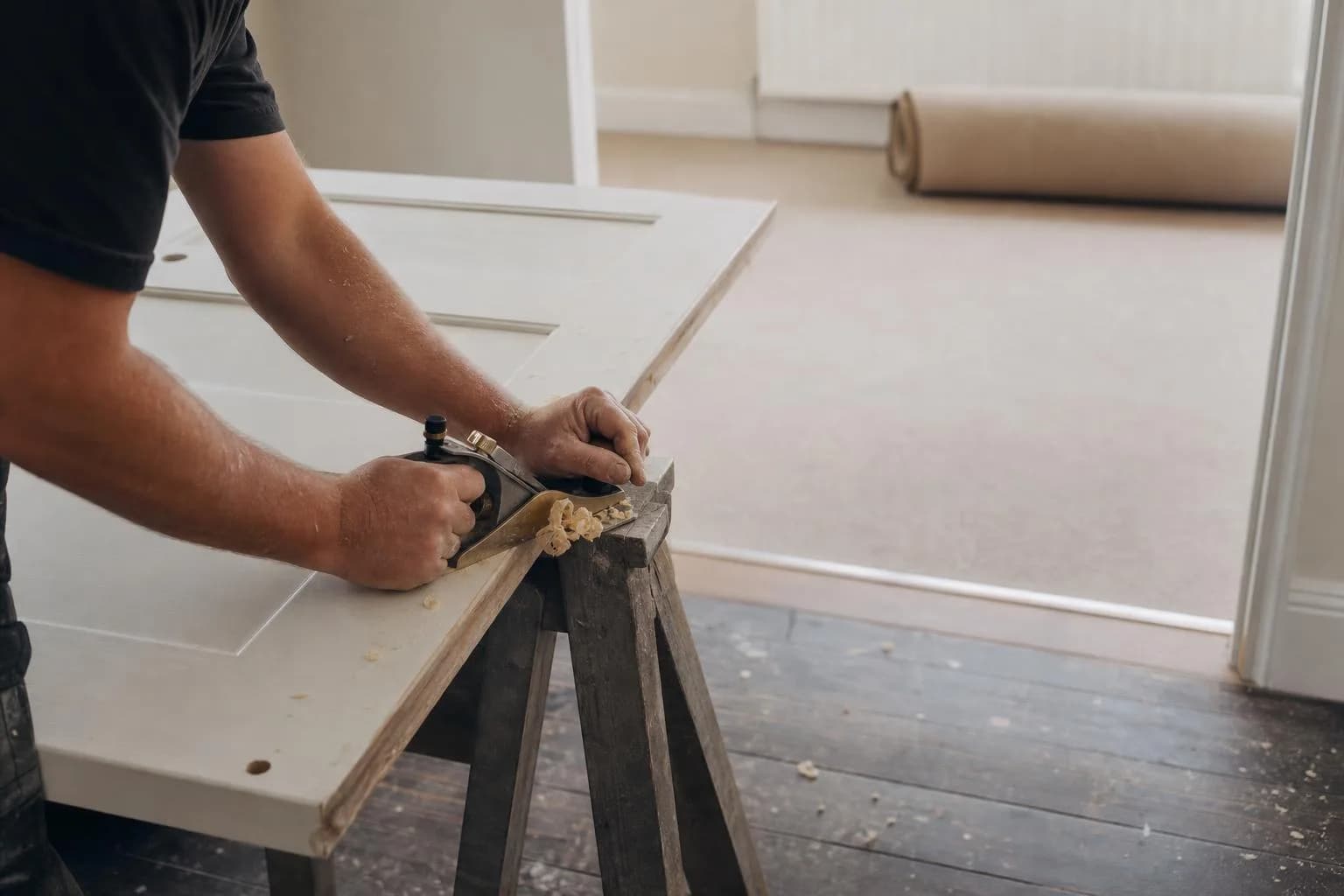 A carpenter planing the bottom of a door so it clears a new carpet