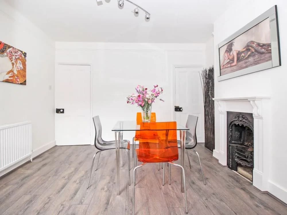 Dining room with white walls, a grey laminate floor and a Victorian fireplace with a white surround