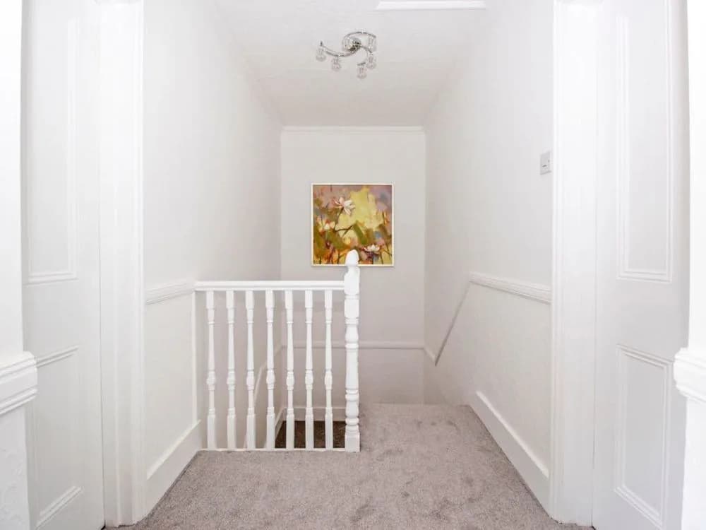 Upstairs landing with white walls and woodwork and a grey carpet