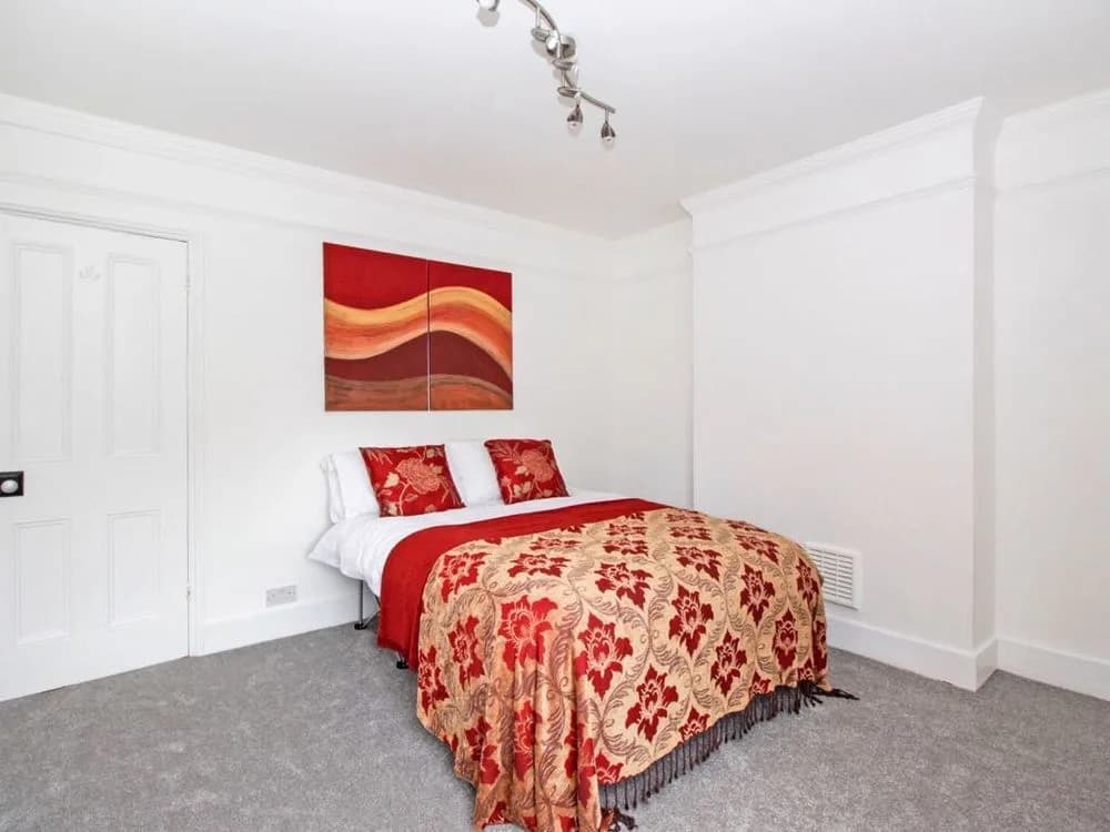 Bedroom with white walls, cornice and a white panelled door