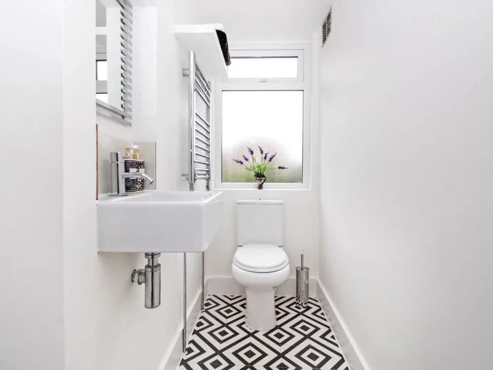Cloakroom with a wall-hung basin, chrome towel rail and a black and white geometric floor