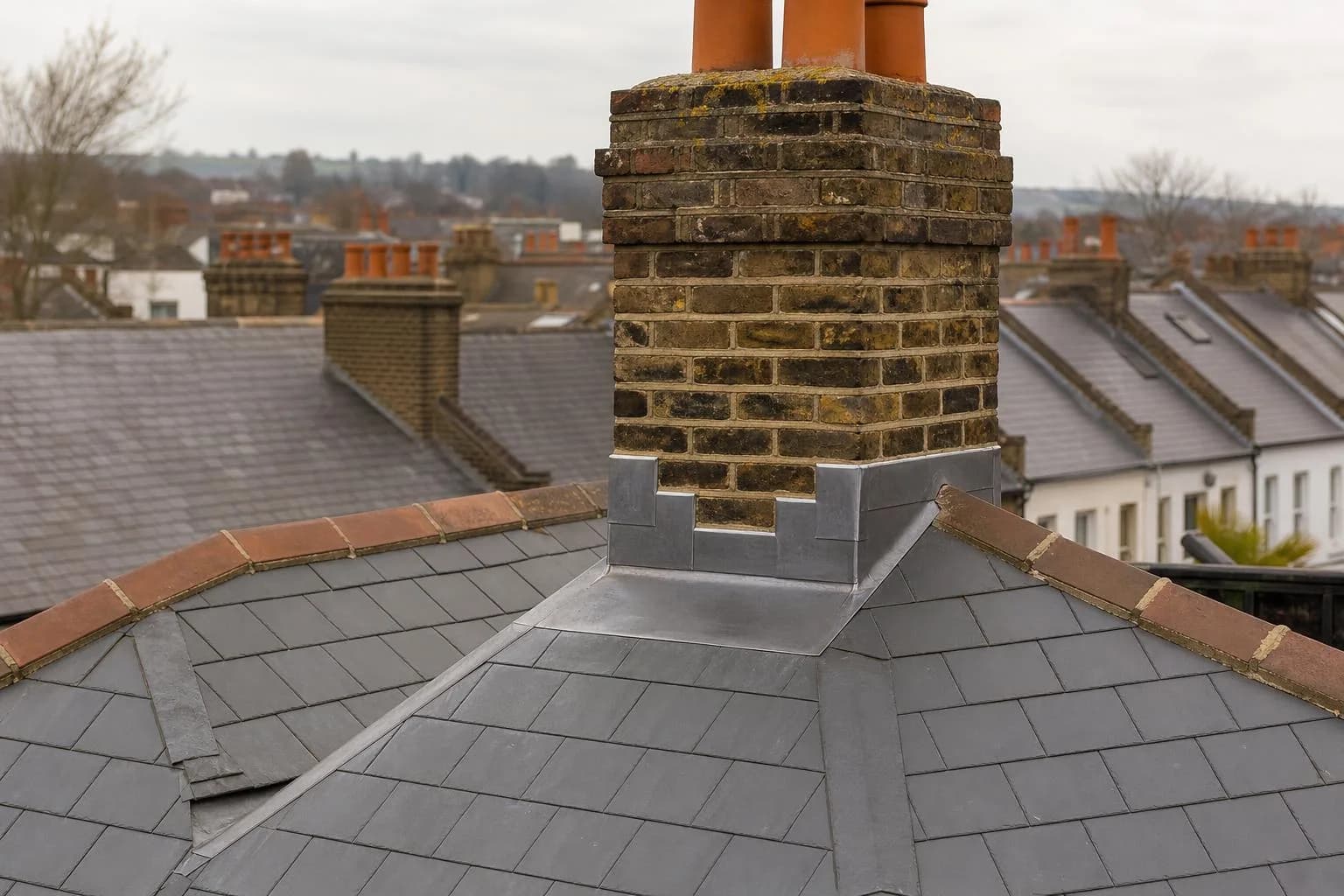 A Victorian slate roof with lead flashing around a chimney